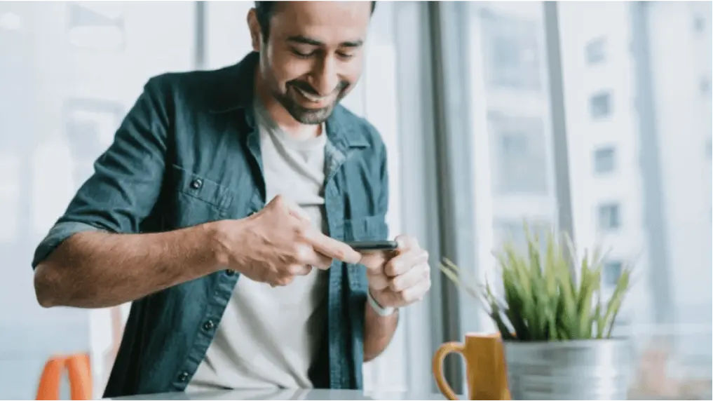 Ein Mann benutzt sein Smartphone im Büro für eine die Aufnahme eines Dokuments.